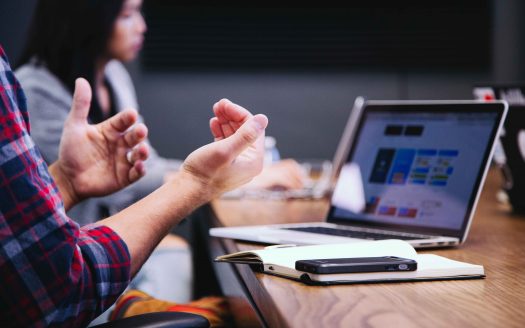 Expressive hands during meeting with computer in background